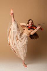 Portrait of a girl with a violin and a bow in her hands on a plain beige background. Music concept