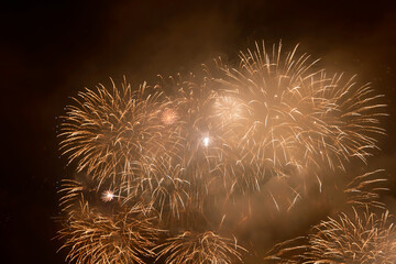 Beautiful yellow fireworks display lights up the sky with dazzling display during New Year celebration. Abstract colored fireworks background with copy space. Celebration and anniversary concept