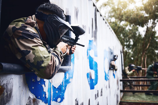 Aim, gun or people in a paintball shooting game with fast action on a fun battlefield on holiday. Man on mission, playing or player with military weapons gear for survival in an outdoor competition