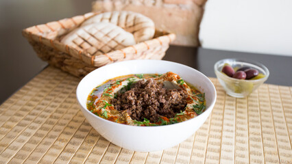 Bowl with hummus and minced pork served with pita bread.