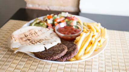Plate with hamburgers, french fries and pita bread.