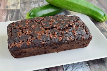 Zucchini chocolate cake. Moist double chocolate cake with grated zucchini, cocoa powder, chocolate and chocolate chips. Shot on wooden background