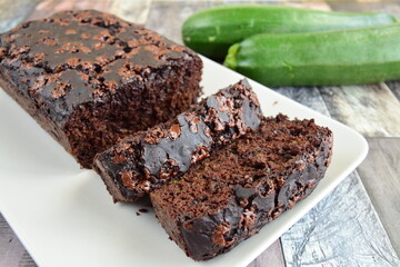 Zucchini chocolate cake. Moist double chocolate cake with grated zucchini, cocoa powder, chocolate and chocolate chips. Shot on wooden background