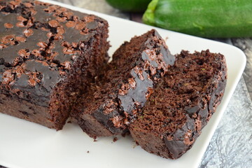 Zucchini chocolate cake. Moist double chocolate cake with grated zucchini, cocoa powder, chocolate and chocolate chips. Shot on wooden background