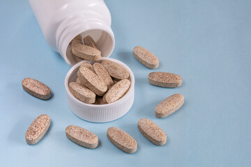 Oblong tablets spilled from a bottle on a blue background
