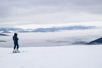 Fototapeta na wymiar The skier rides high in the snow in the mountains. Fog on the mountain and people skiing