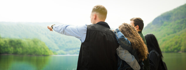 Group of young friends traveling in the forest together.Male pointing with finger the landscape view with happiness and fun.