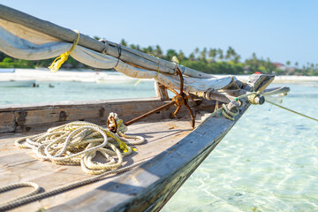 Wooden fisherman boats on sandy beach with blue water background, Zanzibar, Tanzania