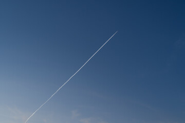 Flying airplane with contrails in the blue sky