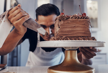 Piping, chef and man baker baking a cake with chocolate in a kitchen or pastry cook preparing a...