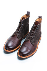 Footwear Ideas. Pair of Premium Dark Brown Grain Brogue Derby Boots Made of Calf Leather with Rubber Sole Placed in Line Together Over White