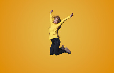 Fototapeta na wymiar Full length body size photo of a woman jumping high gesturing like winner isolated on yellow color background.