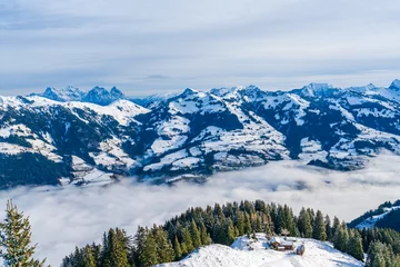 Poster Panoramic aerial view of wintry landscape in Austrian Alps above low clouds covering Kitzbuhel in Austria © beataaldridge