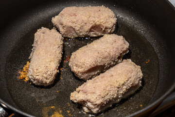 Fresh unfrozen turkey cutlets lie in oil in a frying pan
