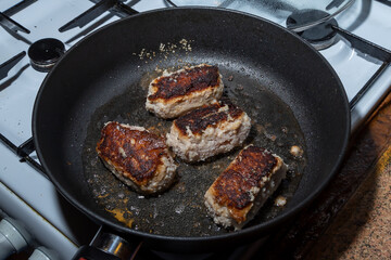 Turkey cutlets fried on one side lie in oil in a frying pan
