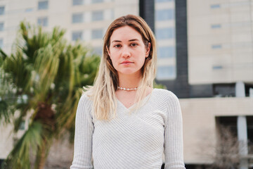 Close up portrait of blonde caucasian young woman looking serious at camera. Pretty teenage girl...