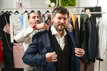 Client trying on jacket aided by tailor