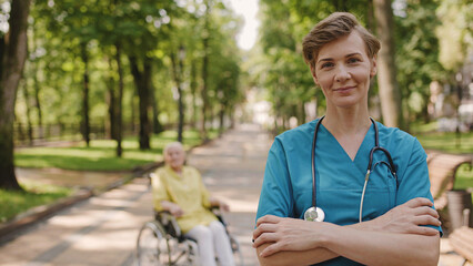 Portrait of professional physician smiling on camera, woman with disability on background