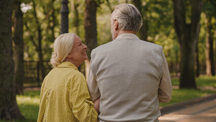 Sweet elderly couple walking in park together, enjoying conversation on a date in park