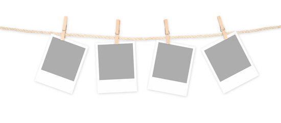 Four blank polaroid frames and clothespins attached to a rope isolated on white background....