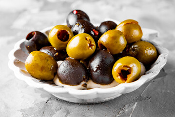 Delicious black and green olives in plate on gray background