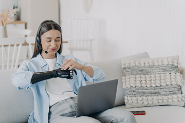 Disabled caucasian young woman in headset has online conference on laptop. Equal rights.