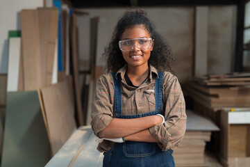 Portrait of African American female carpenter standing with arms crossed at wood processing plants....