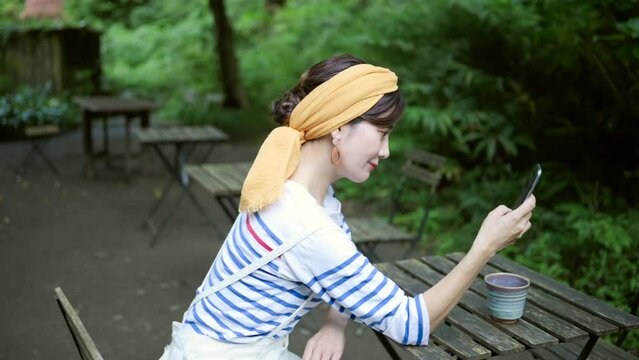 公園でスマートフォンを操作するアジア人女性	