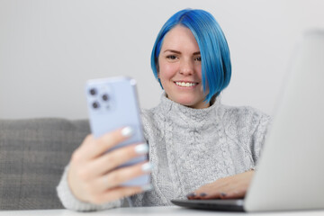 Friendly millennial woman with dyed blue hair communicating on video call. Freelancer female person...