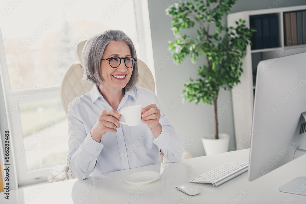 Sticker Photo of cheerful company owner lady sitting chair hold fresh hot coffee mug look monitor webinar workplace indoors