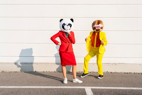 Man and woman wearing animal masks standing in front of wall
