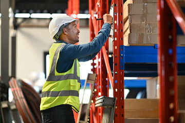 Side view of warehouse worker checking goods and supplies on shelves in large warehouse distribution center environment