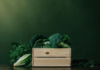 Crate full of fresh raw vegetables in front of green wall
