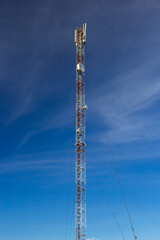 Telecommunication tower for mobile phone with antennas over a blue sky. Distribution function of...