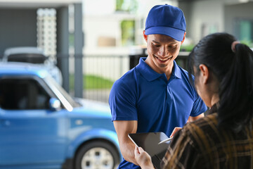 Cropped shot of delivery man in blue uniform using digital tablet while standing at open van full of delivering package