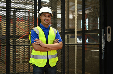 Portrait of male storehouse manager wearing hard hats and reflective jackets standing with crossed arms against goods shelf