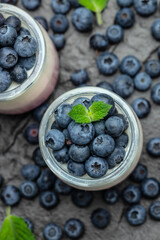 Homemade dessert Panna cotta with blueberry berries and jelly in jars on a dark background. Delicious balanced food concept. place for text, top view