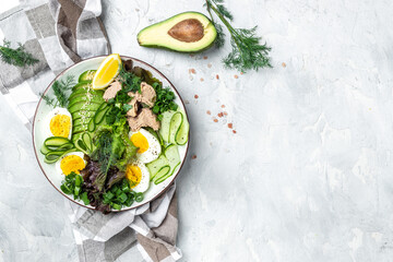 Ketogenic low carbs diet, Plate with keto foods: two eggs, avocado, tuna, cucumber and fresh salad. Healthy fats, clean eating for weight loss. top view