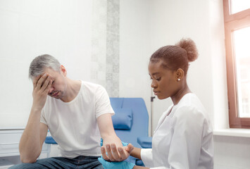 Fototapeta premium An African-American female doctor soothes a patient suffering from a severe headache