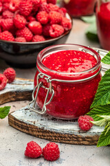 Homemade raspberry jam in jar with raspberries and mint. vertical image. top view. place for text
