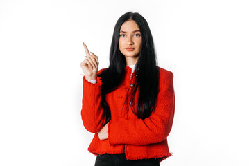 Young brunette woman pointing finger at banner, showing text advertisement or copy space. Indoor studio shot on white background