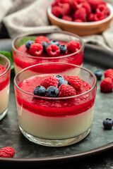 Italian dessert. Raspberry Panna cotta with raspberry jelly on a dark background. Berry dessert with cream sauce in small jars