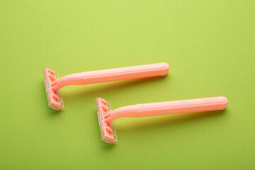 Pink razors for hair removal on green background