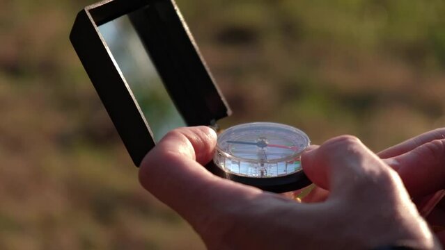 man is looking for direction with a compass in his hands. search for the cardinal directions. active lifestyle, recreation and travel on nature. orientation on the terrain. closeup.