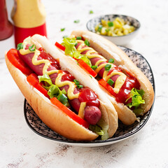 Hot dog with grilled sausage, tomato and lettuce on light background. American hot dog.