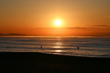Surfers on the beach at dawn in winter.