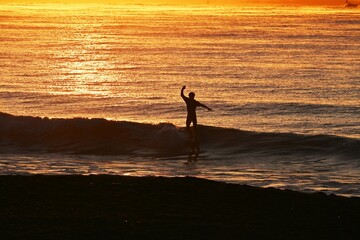 Fototapeta na wymiar Surfers on the beach at dawn in winter.