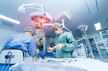 Medical team performing surgical operation in bright modern operating room. Medical devices for...