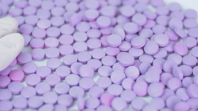 Production of tablets conveyor. Pills Purple color close-up Macro latex glove Pharmacy Medical