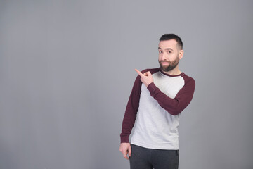 Young man standing pointing to copy space in studio shot - 565303037